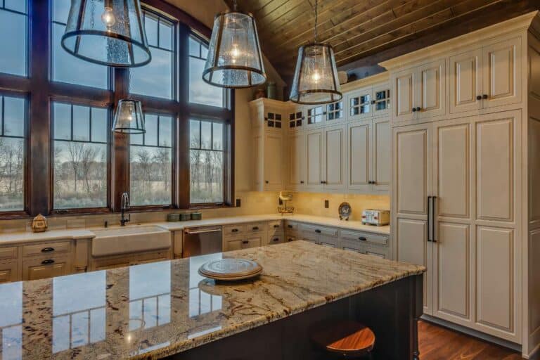 View of kitchen cabins, counter, lighting, and windows in South Bend. Cabinets are white with black handles