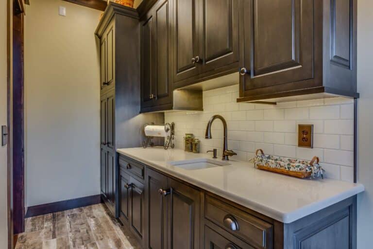 View of bathroom cabinets, and sink in South Bend Indiana with dark brown paint and white tile