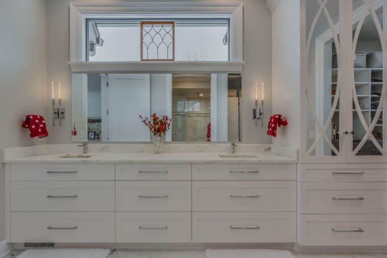 View of white bathroom vanity in Granger Indiana with red flowers and cabinets