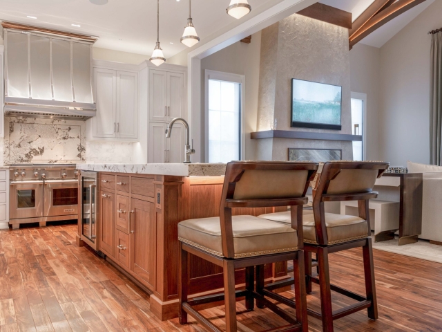 Wide shot of kitchen cabinets, kitchen chairs, and island