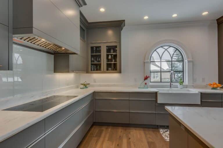 Side view inside kitchen with focus on glass cabinets to left of sink and window